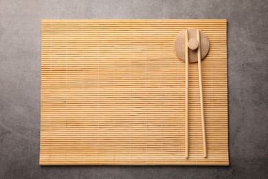 Photo of Bamboo mat and chopsticks on grey table, top view. Space for text