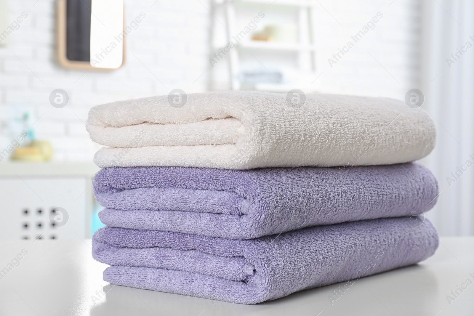 Photo of Stack of fresh towels on table in bathroom, closeup