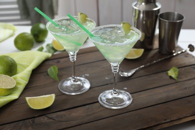 Photo of Delicious Margarita cocktail in glasses and lime on wooden table