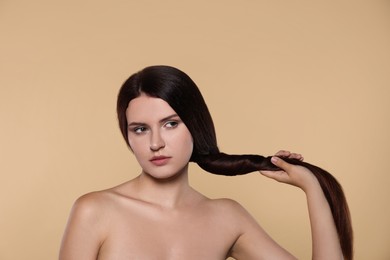 Portrait of beautiful young woman with healthy strong hair on beige background