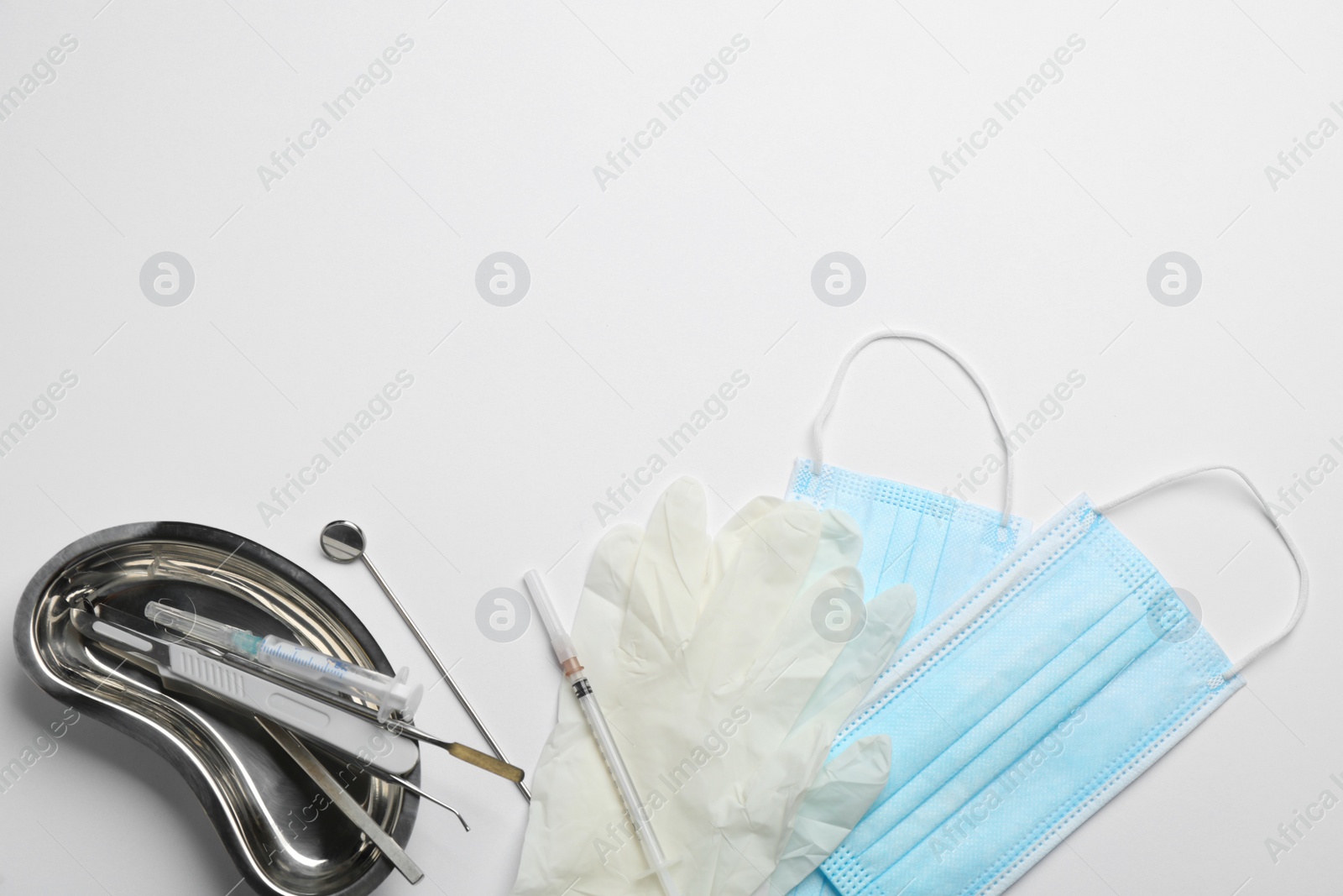 Photo of Set of different dentist's tools, face masks and gloves on light background, flat lay. Space for text