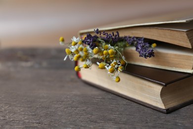 Photo of Closed books with beautiful dried flowers on wooden table, closeup. Space for text