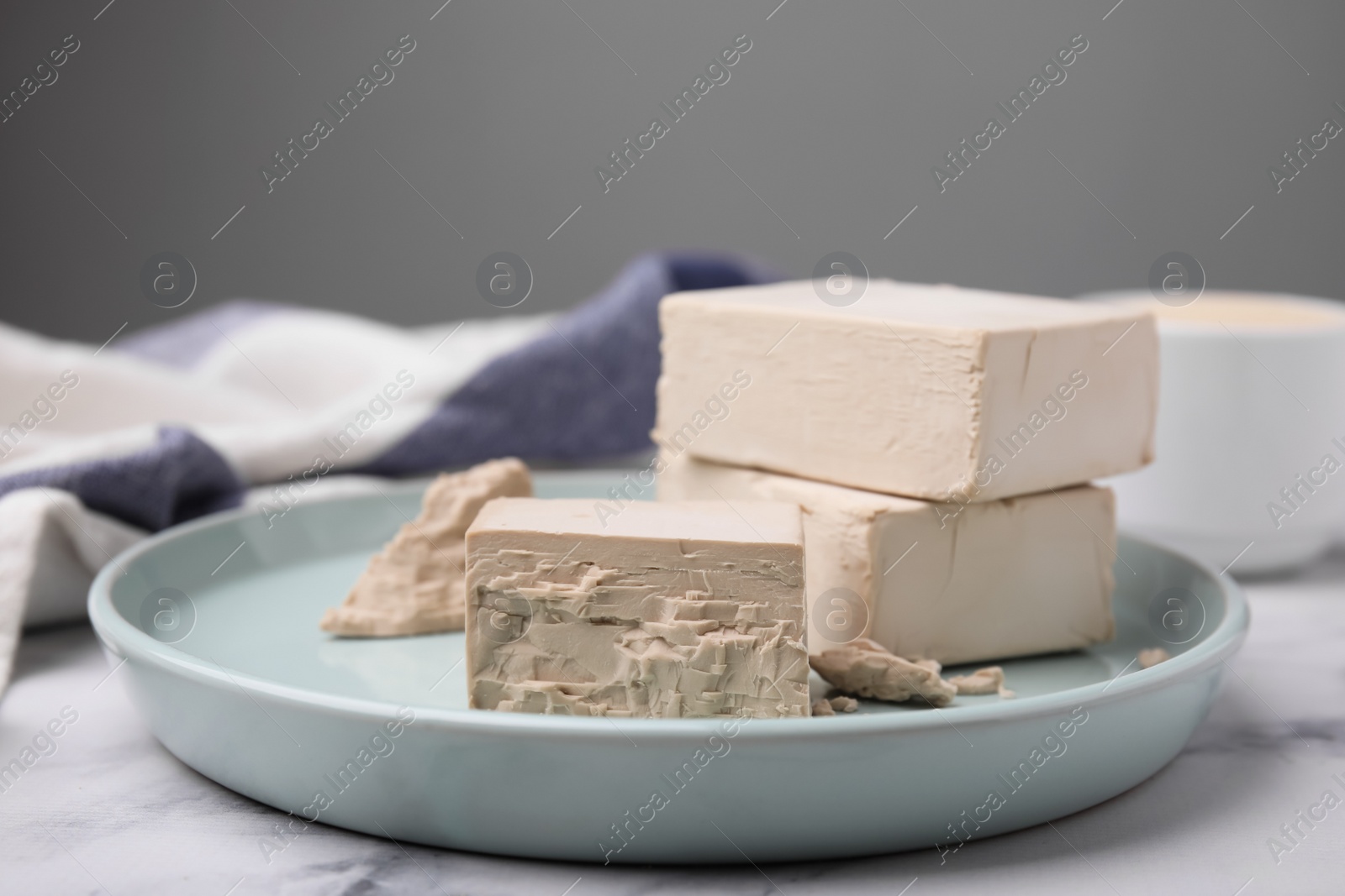 Photo of Blocks of compressed yeast on turquoise plate, closeup