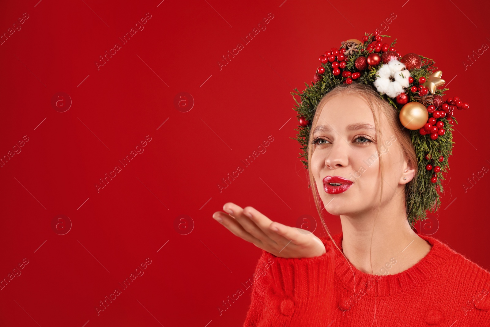 Photo of Beautiful young woman wearing Christmas wreath on red background. Space for text