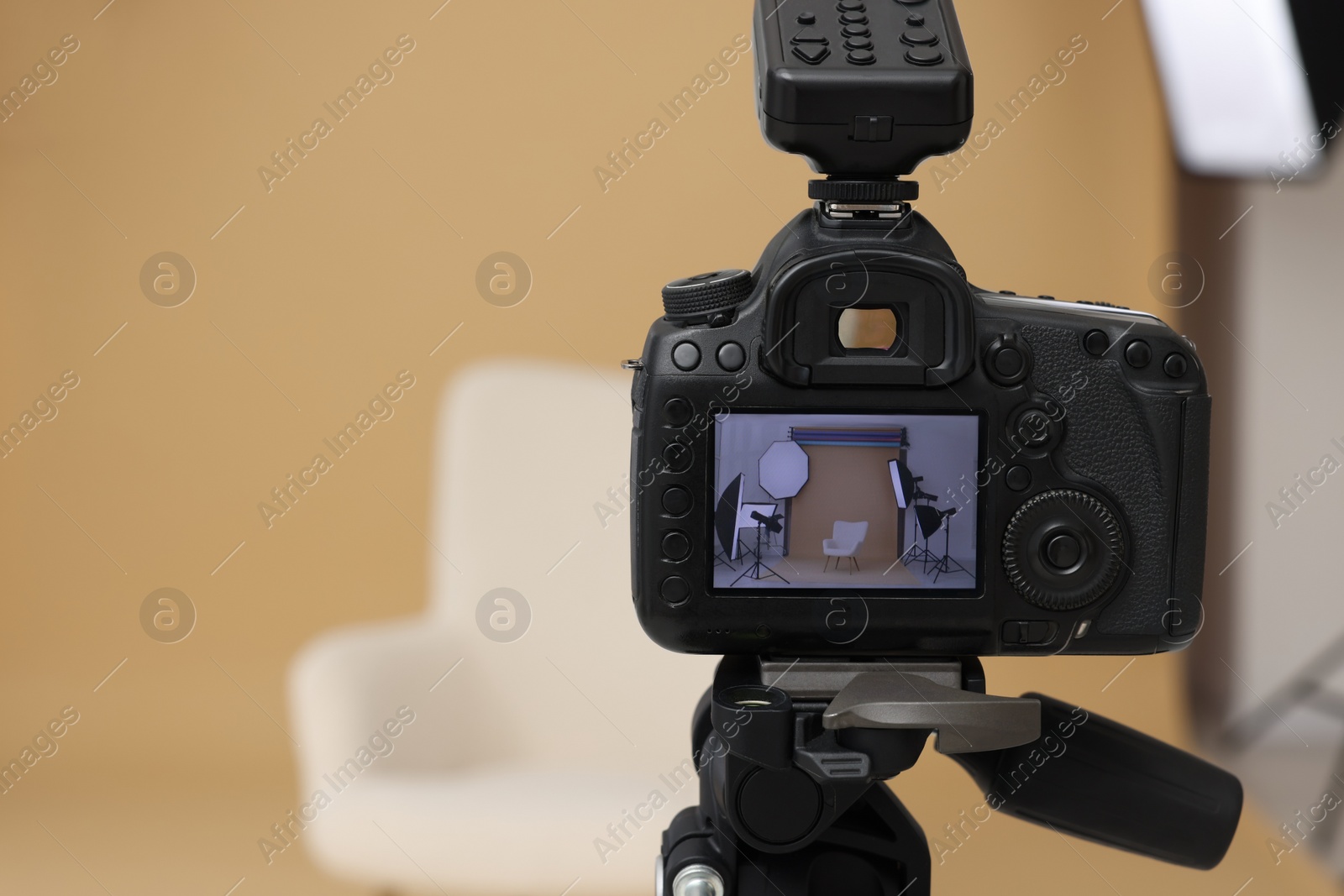 Photo of Camera on tripod, armchair and professional lighting equipment in modern photo studio, closeup. Space for text