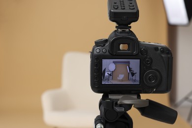 Camera on tripod, armchair and professional lighting equipment in modern photo studio, closeup. Space for text