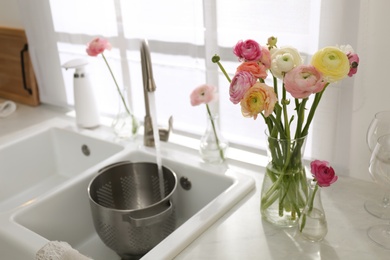 Photo of Light kitchen decorated with beautiful fresh ranunculus flowers