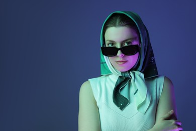 Portrait of beautiful young woman with sunglasses on color background with neon lights