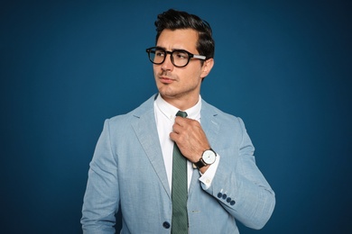 Photo of Portrait of handsome young businessman wearing glasses on blue background