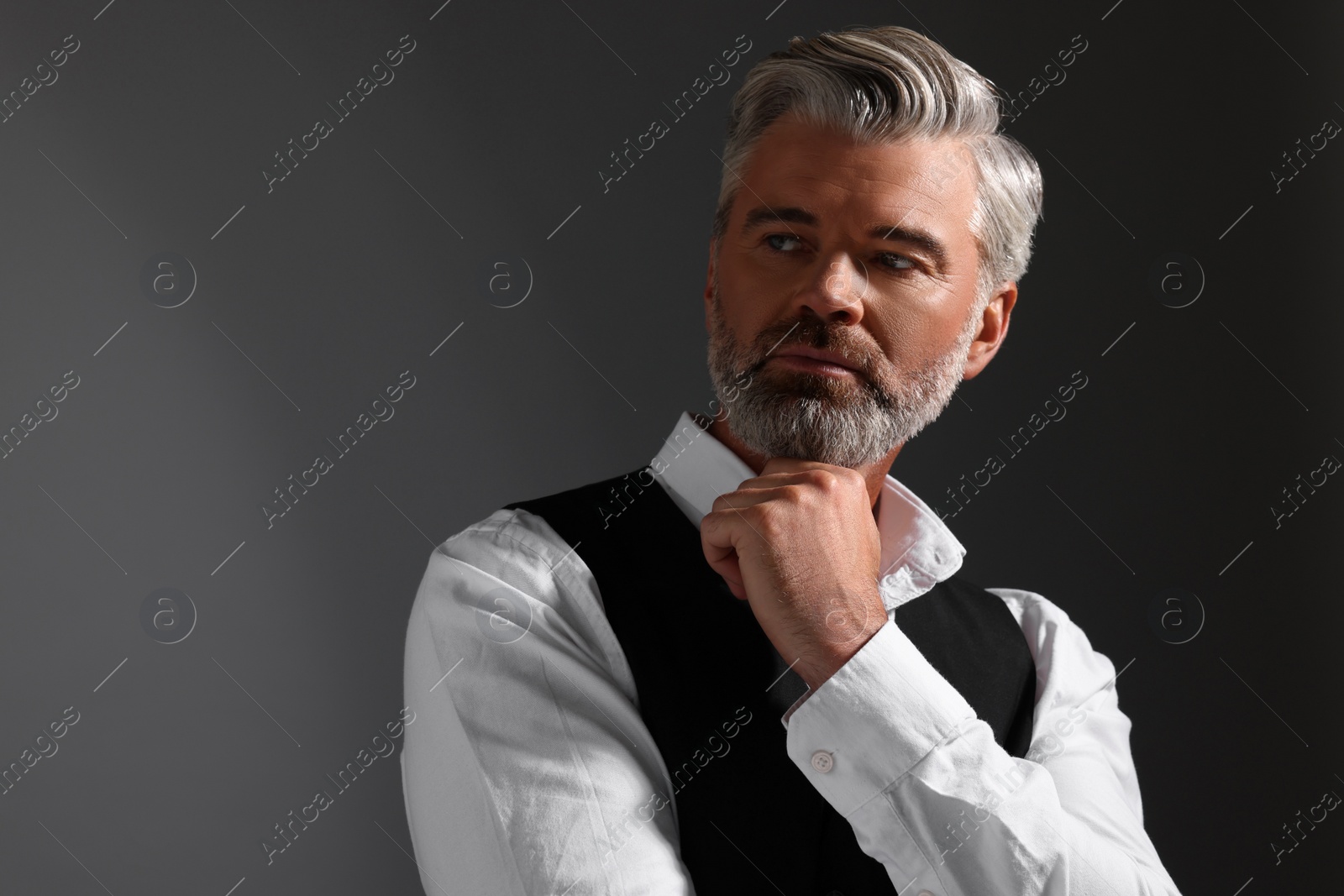 Photo of Portrait of confident man with beautiful hairstyle on dark background. Space for text