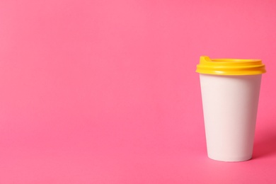Photo of Takeaway paper coffee cup on pink background. Space for text