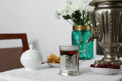Photo of Traditional Russian samovar, aromatic tea and treats on table indoors
