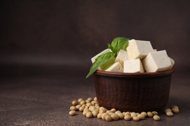 Photo of Delicious tofu cheese, basil and soybeans on brown textured table, closeup. Space for text