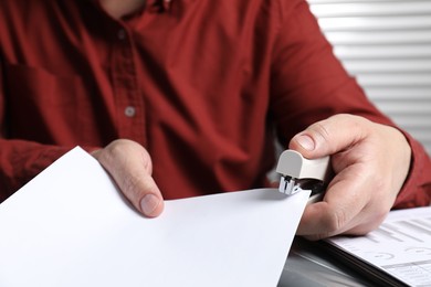 Photo of Man with papers using stapler at table, closeup