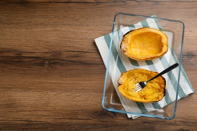 Photo of Halves of cooked spaghetti squash in baking dish on wooden table, top view Space for text
