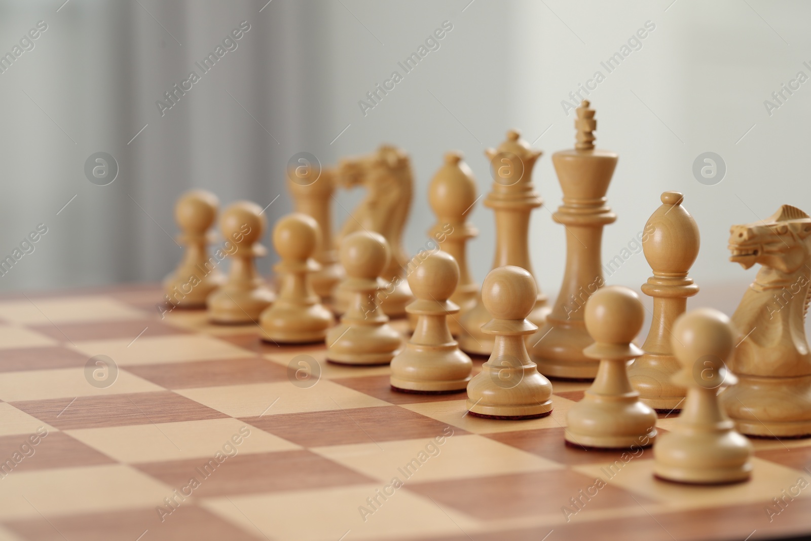 Photo of Chess board with white wooden pieces, closeup. Space for text