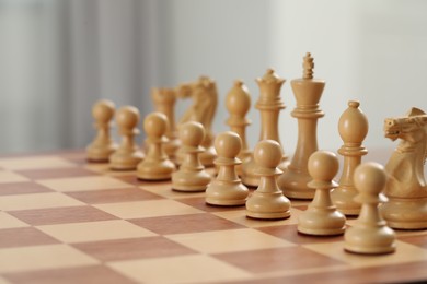 Photo of Chess board with white wooden pieces, closeup. Space for text
