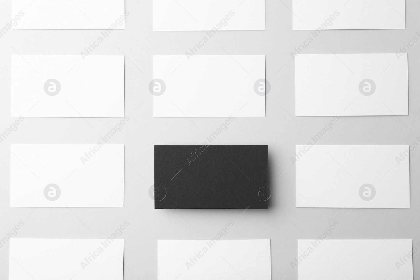 Photo of Blank black and white business cards on light background, flat lay. Mockup for design