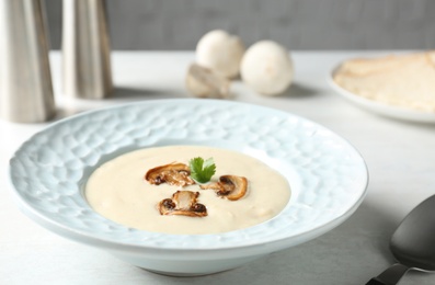 Photo of Delicious cream soup with mushrooms on white table