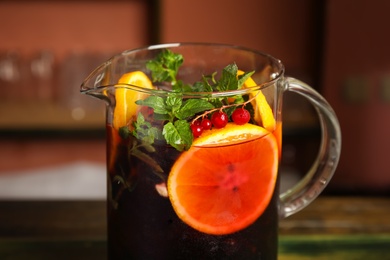 Photo of Jug with delicious refreshing cocktail on blurred background, closeup