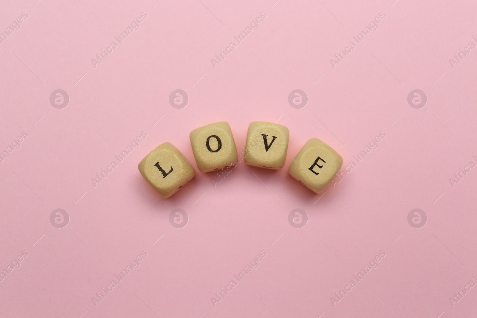 Photo of Mini cubes with letters forming word Love on pink background, flat lay