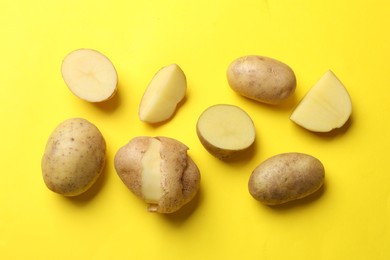 Photo of Fresh raw potatoes on yellow background, flat lay