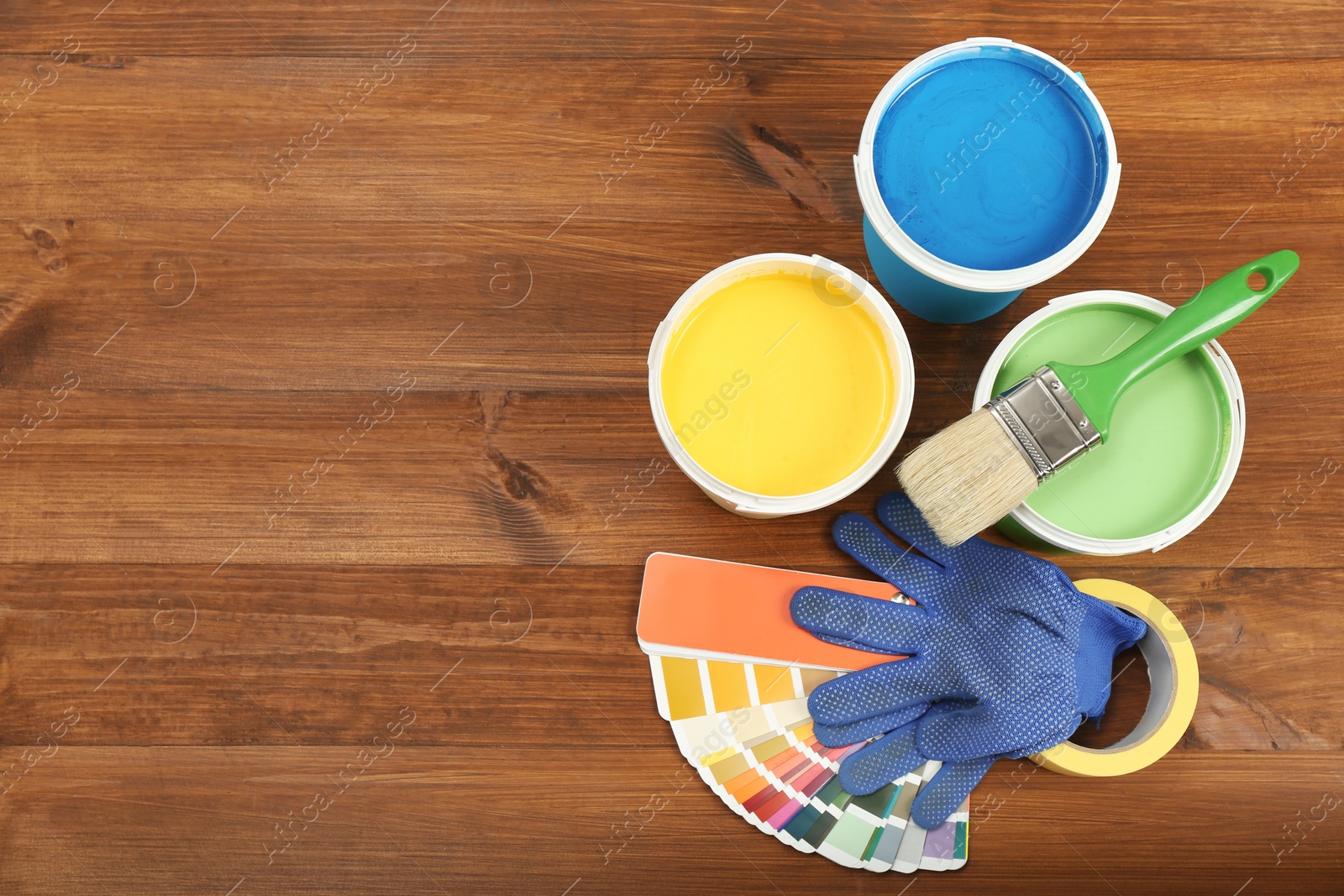 Photo of Buckets of paints, palette and decorator's accessories on wooden background, flat lay. Space for text