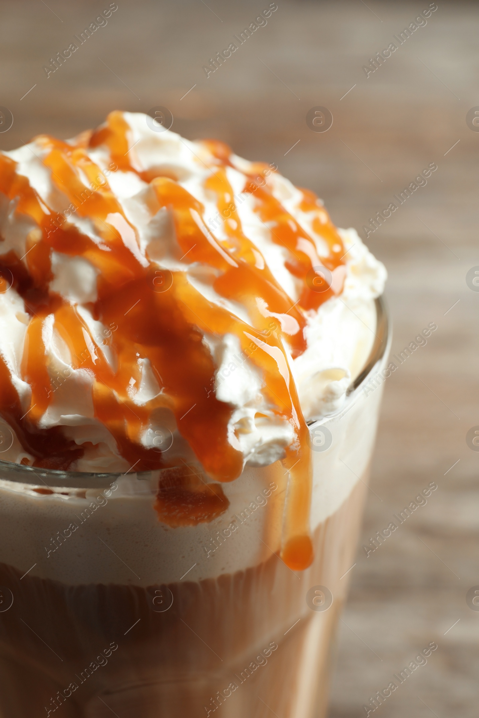 Photo of Glass of coffee with caramel topping on table, closeup