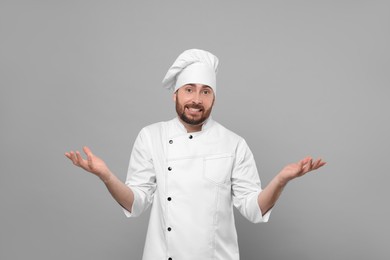 Puzzled mature male chef on grey background