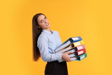 Photo of Disappointed woman with folders on orange background