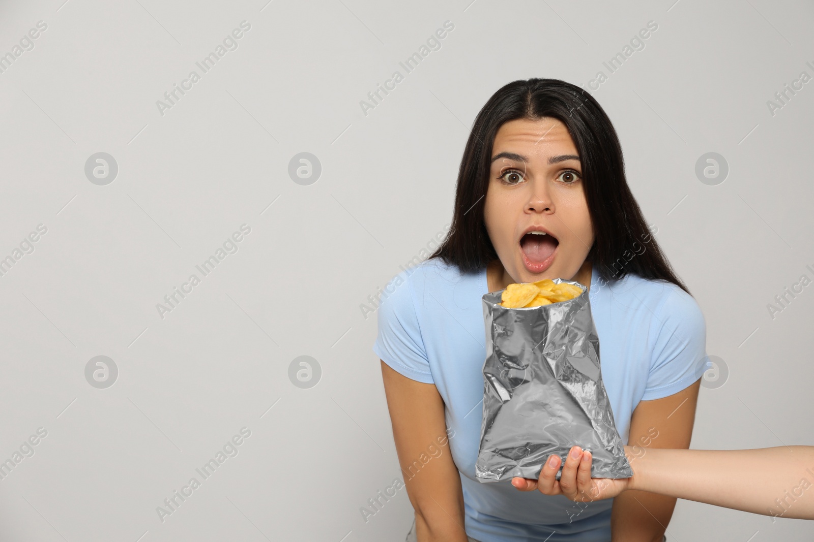 Photo of Beautiful young woman with tasty potato chips on grey background, space for text