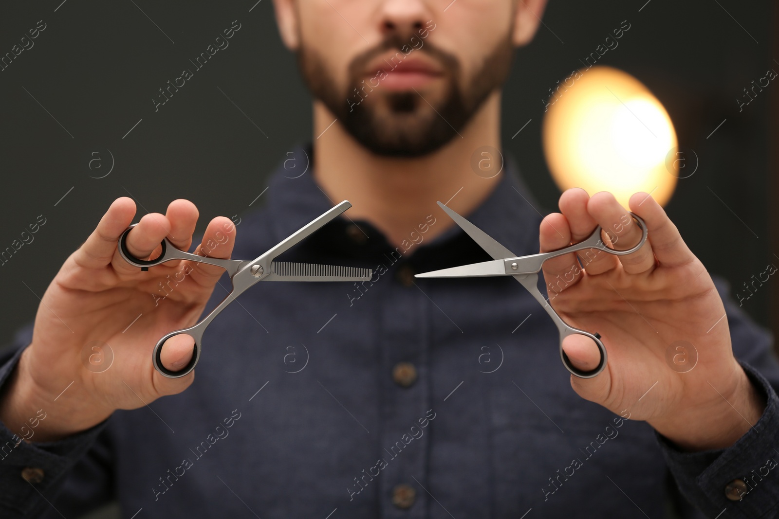 Photo of Hairstylist holding professional scissors in beauty salon, closeup