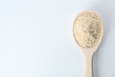 Photo of Spoon of sesame flour isolated on white, top view with space for text