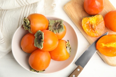 Photo of Delicious fresh persimmons on white wooden table, flat lay