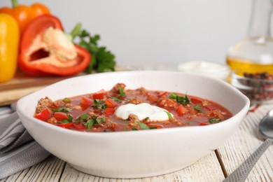 Photo of Bowl of delicious stuffed pepper soup on white wooden table