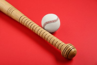 Photo of Wooden baseball bat and ball on red background. Sports equipment