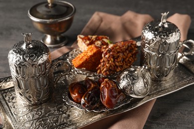 Photo of Tea, date fruits and Turkish delight served in vintage tea set on grey textured table
