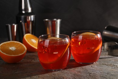 Photo of Aperol spritz cocktail, ice cubes and orange slices in glasses on grey textured table