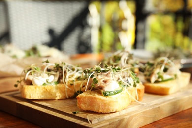 Delicious bruschettas with fish on wooden table