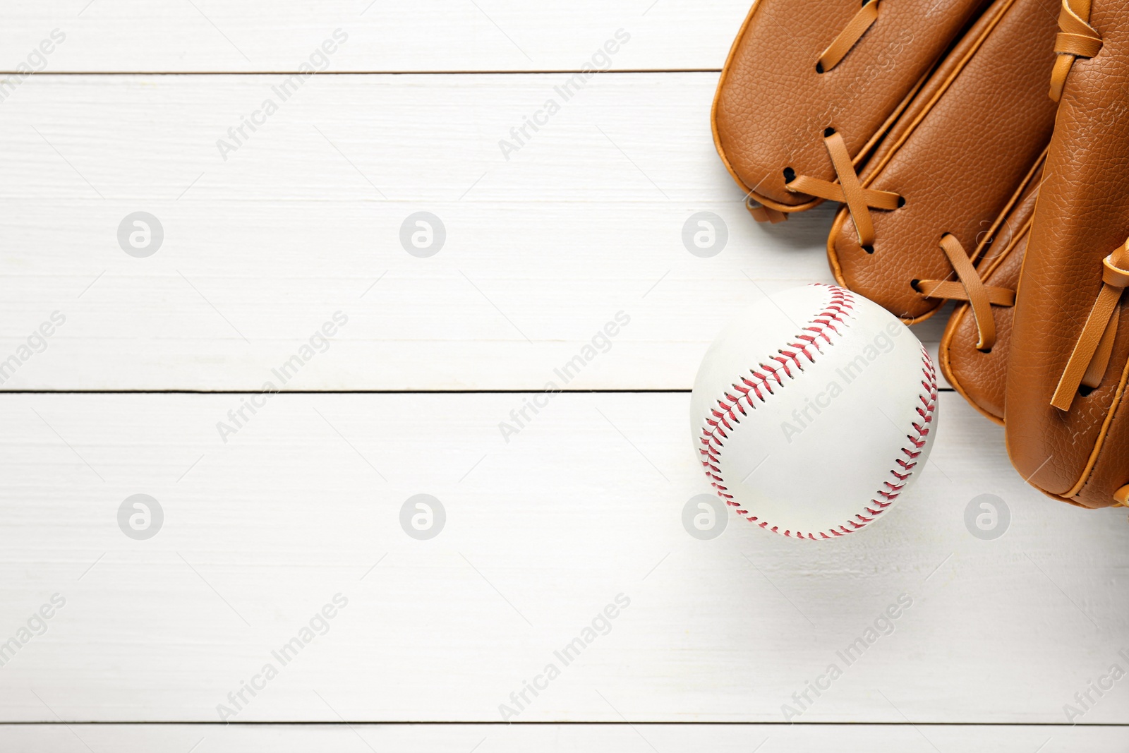 Photo of Catcher's mitt and baseball ball on white wooden table, top view with space for text. Sports game