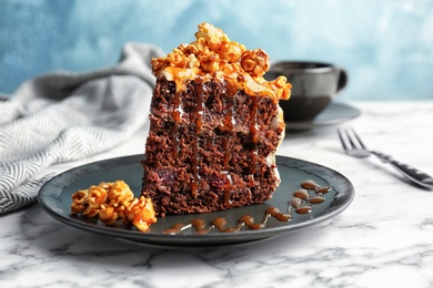 Piece of delicious homemade cake with caramel sauce and popcorn on table