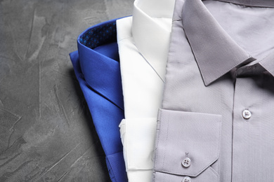 Stylish shirts on grey stone table, closeup. Dry-cleaning service