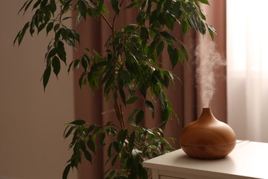 Photo of Air humidifier near houseplant on white table indoors