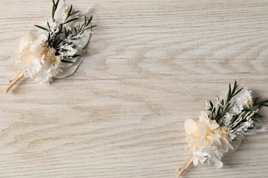 Photo of Stylish boutonnieres on white wooden table, top view. Space for text