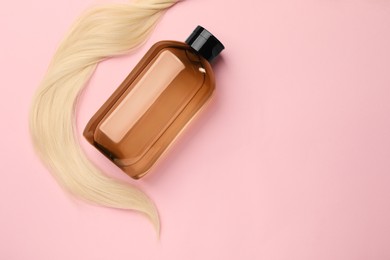 Photo of Lock of hair and shampoo bottle on pink background, flat lay, space for text