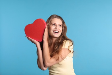 Portrait of young woman with decorative heart on color background