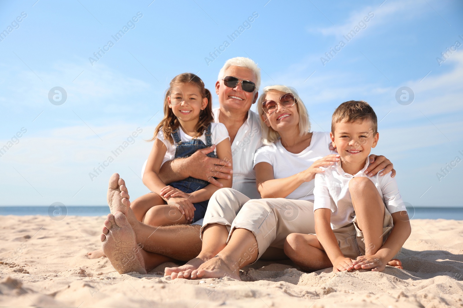 Photo of Cute little children with grandparents spending time together on sea beach