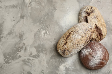 Photo of Different kinds of fresh bread on grey table, flat lay. Space for text