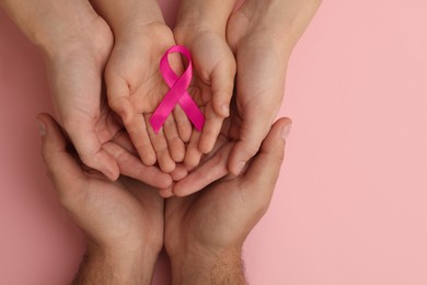 Photo of Family holding pink ribbon on color background, top view. Breast cancer awareness