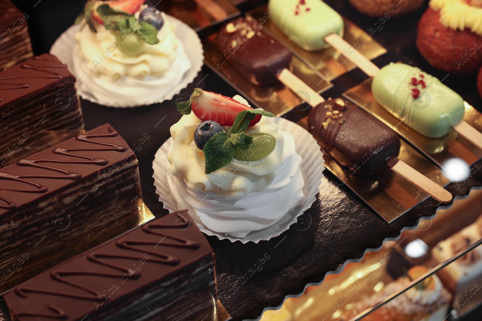 Photo of Different tasty desserts on counter in bakery shop, closeup